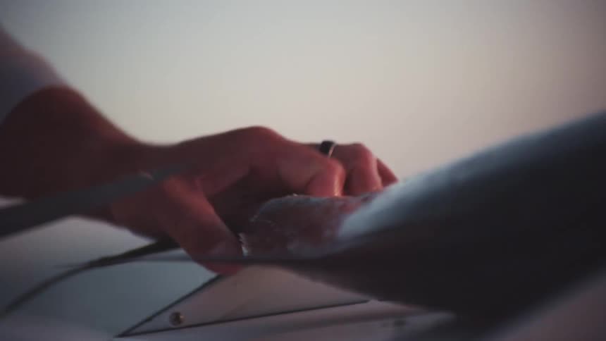 Close up of the hands of a man using a sharp kitchen knife to cut the tail of a fish