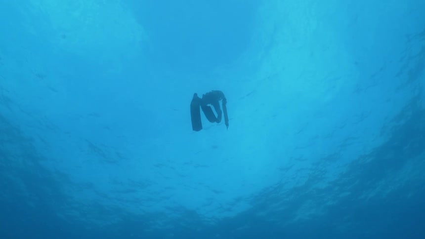 Underwater footage of a free diver floating under the surface in the blue ocean waters