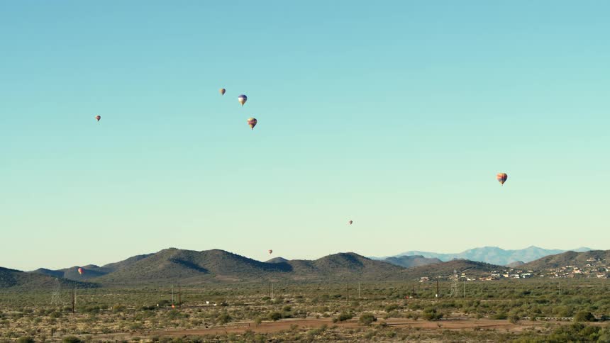 Colorful hot air balloons float in a clear sky over Scottsdale, AZ