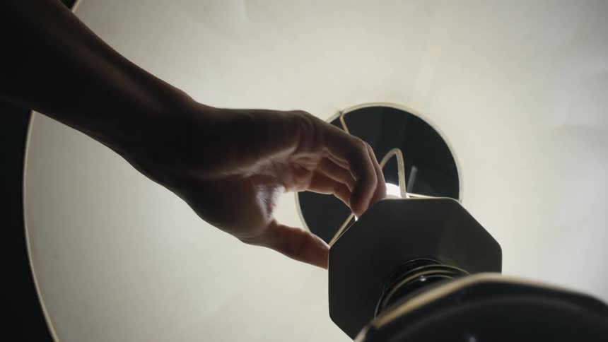 A woman turns off a table lamp