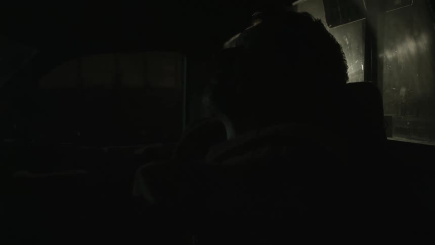 Man silhouetted in vehicle smiles while holding arms extended for selfie