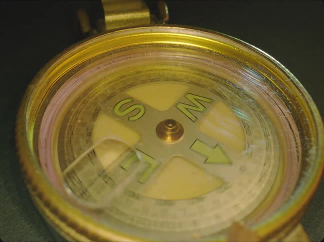 Light shines on a gold compass as it spins around