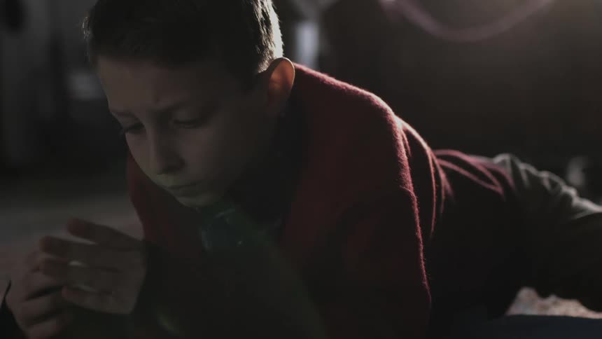 A little boy is lying on the floor playing with a toy in his hands