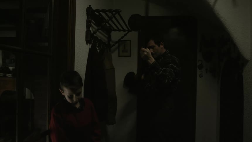 Man holding and testing a shotgun at home pushes a boy standing next to him