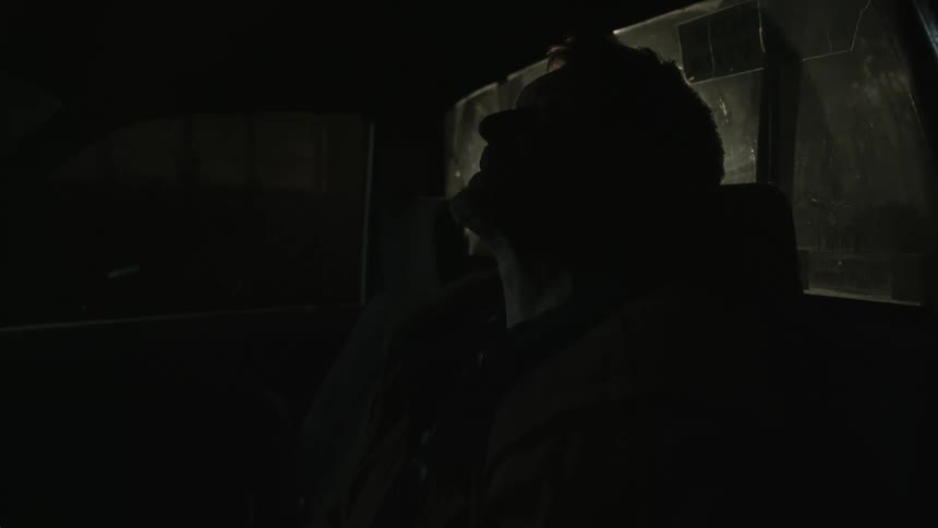 A man sits in a vehicle at night and sings