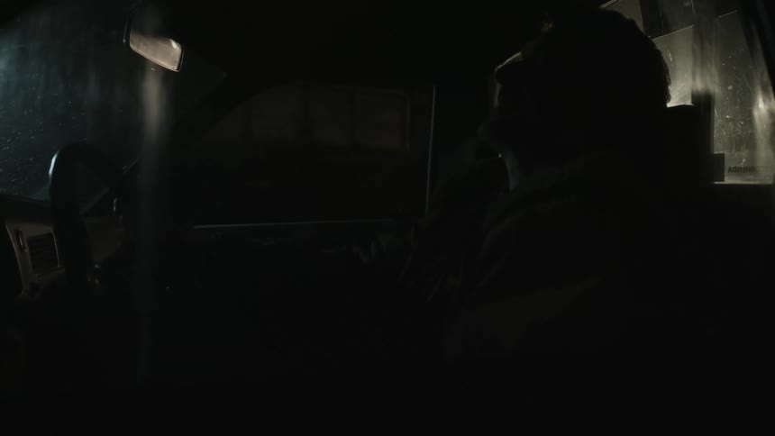 An upset male is sitting in a vehicle at night