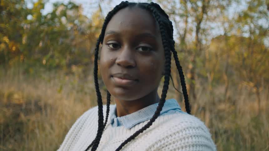 A portrait of a girl standing outdoors in a field