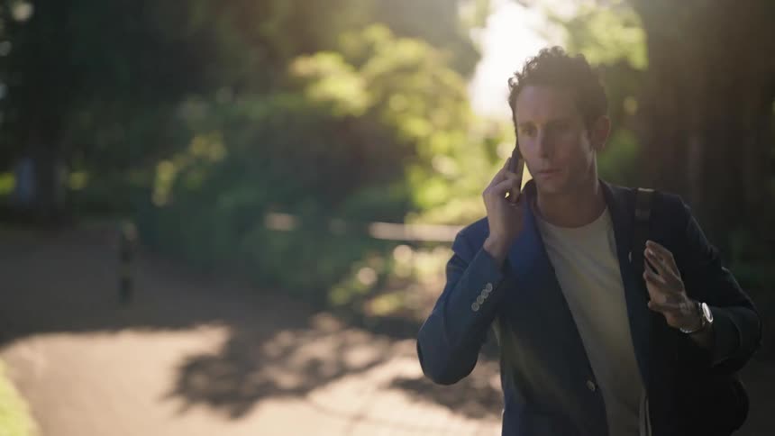 A man talks on his cell phone while walking along a path outdoors