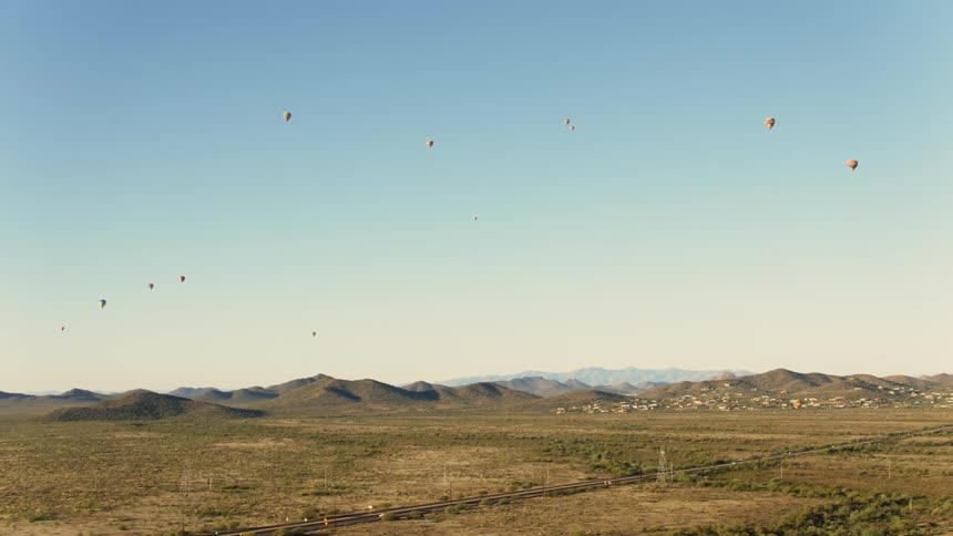 Tracking Shot of Hot Air Balloons over the Desert