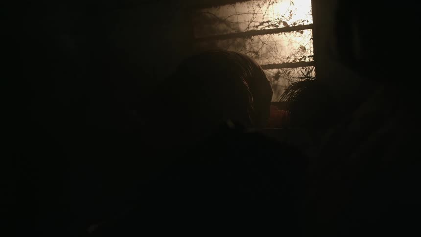 Silhouette of a weak man slowly standing up inside a room in front of a dirty window