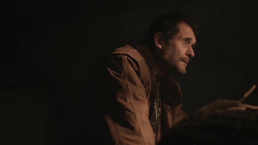 Middle aged man wearing brown jacket gets mad in dark room