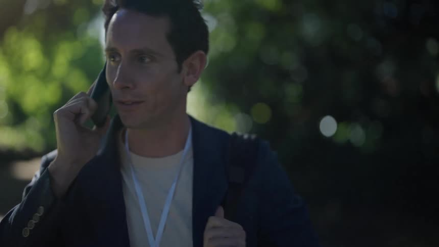 A young man walks outside as he talks on his cellphone