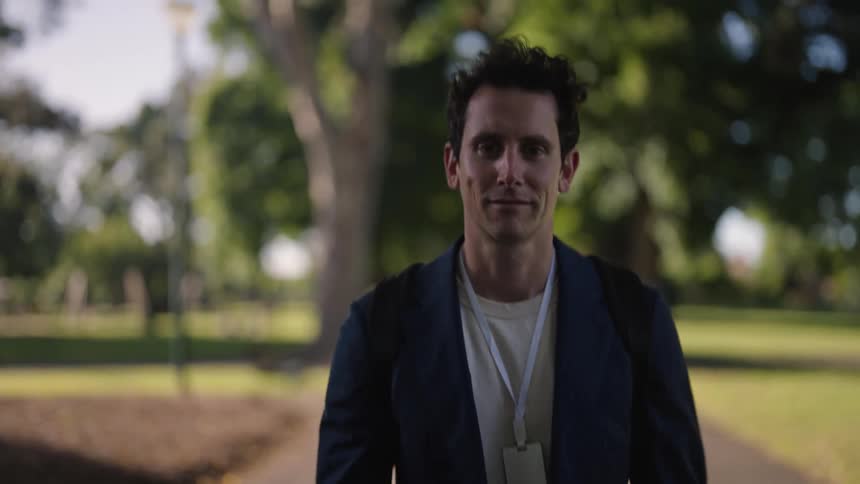 A young man smiles as he walks through a public park