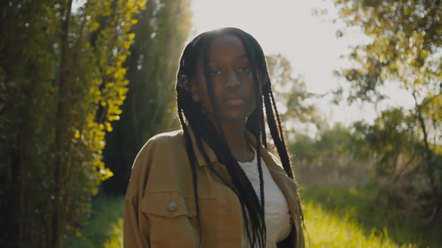 A black girl stands in the woods staring at the camera