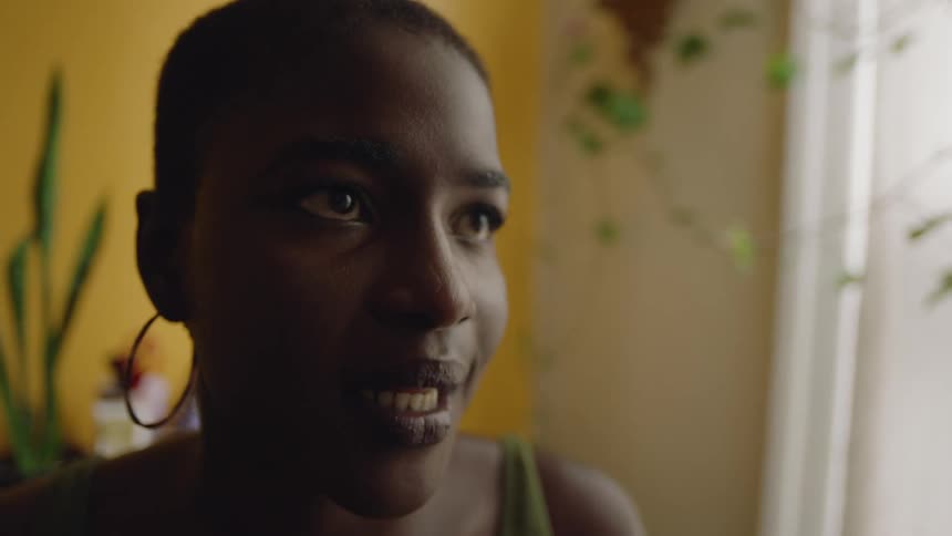 A woman is sitting in a bright room talking to someone