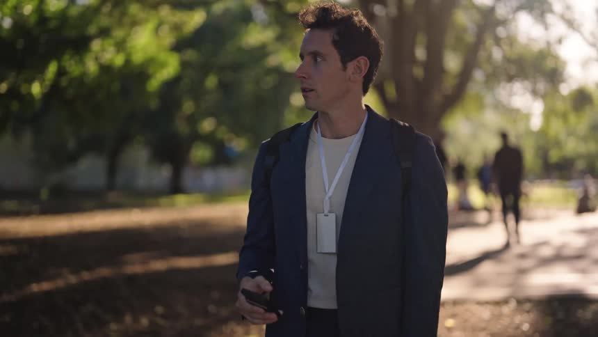 A young white man is looking at his watch and looks like he is late for something