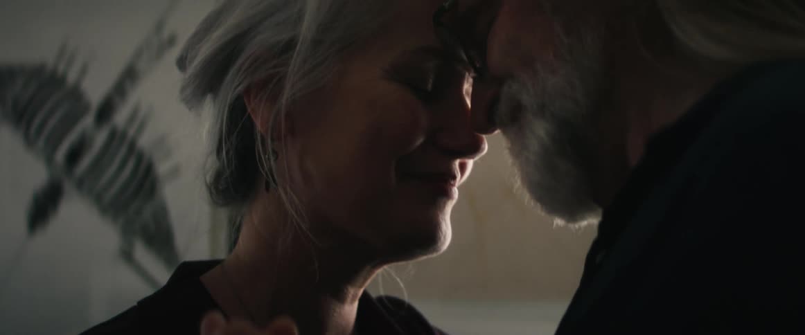 An elderly couple swaying closely to each other