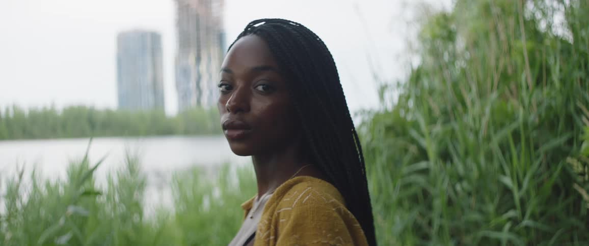 Young woman standing next to a river in the city outskirts looking at the camera
