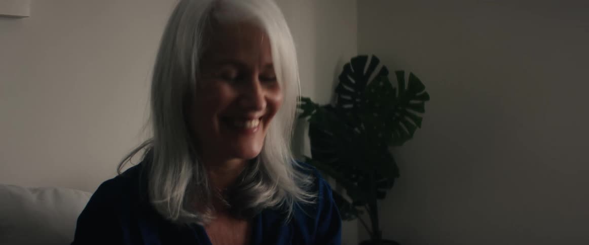 An older woman is smiling and talking to someone else