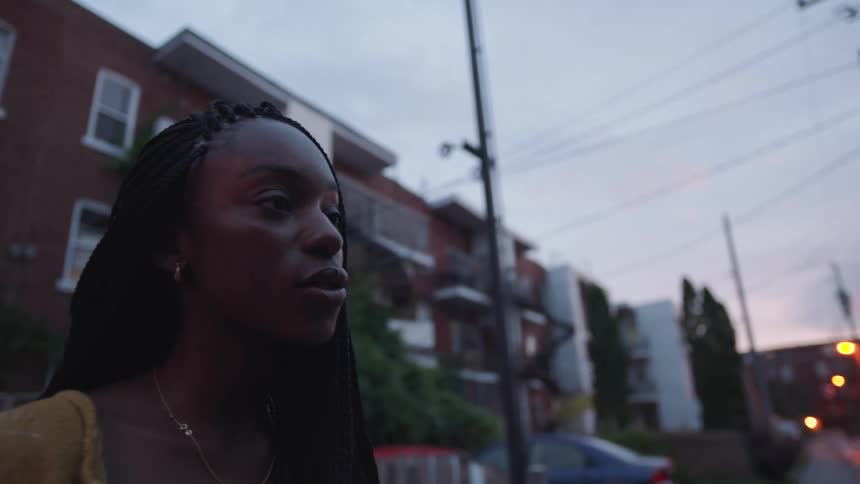 A woman nods and talks as she stands outside apartment buildings