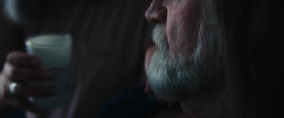 Woman gives an elderly bearded man his medication with a glass of water