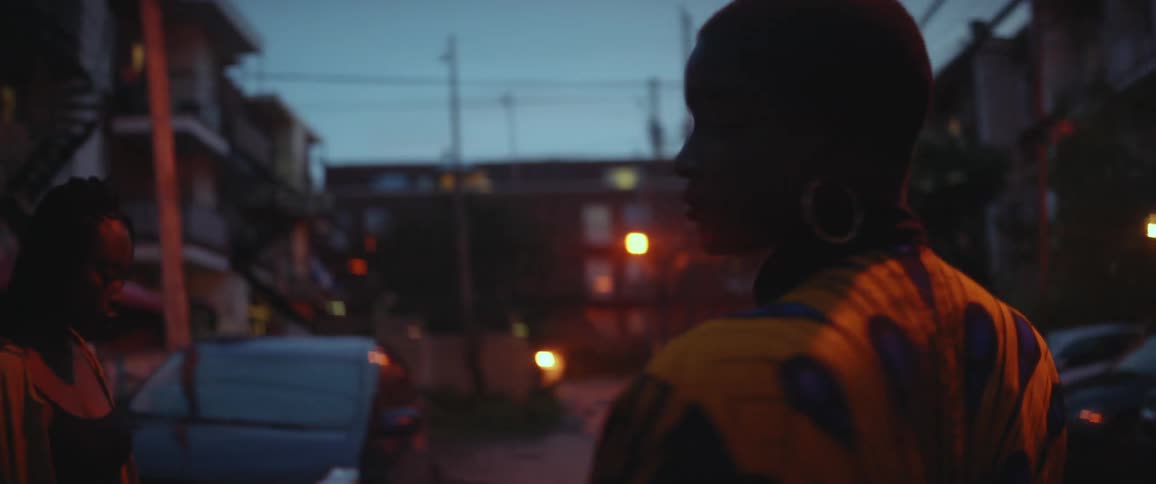Two teenagers are walking outside in the dark around the city area