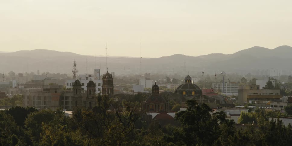 Towers and domes on a castle or church in the city next to the mountains at evening