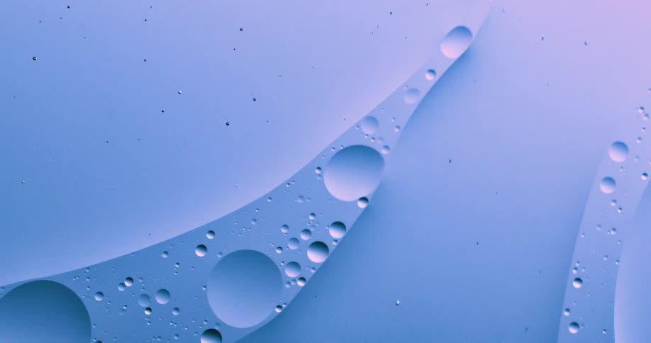 Round bubbles of various sizes floating and flowing on a blue and magenta liquid