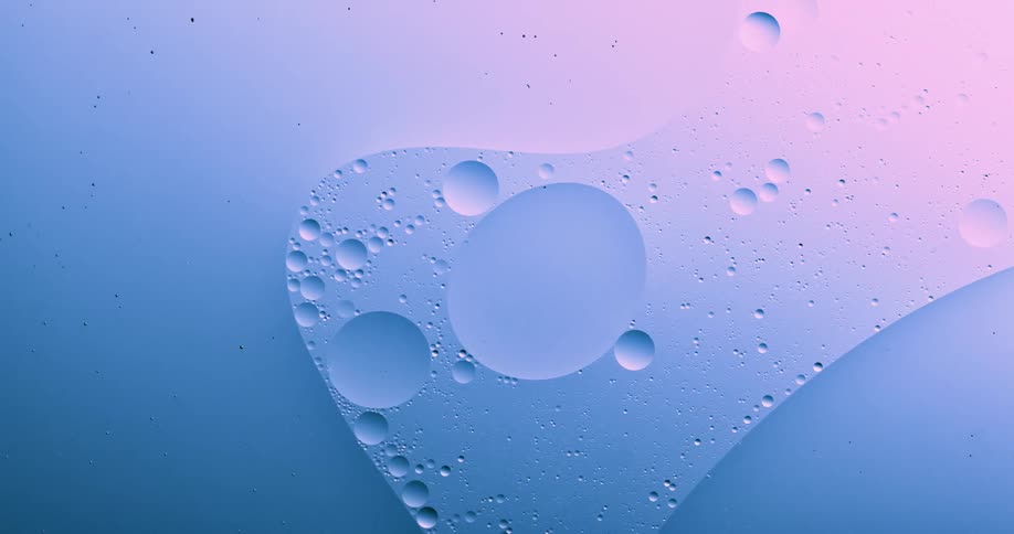 Blobs and bubbles of translucent liquid gently flowing over a blue and magenta background