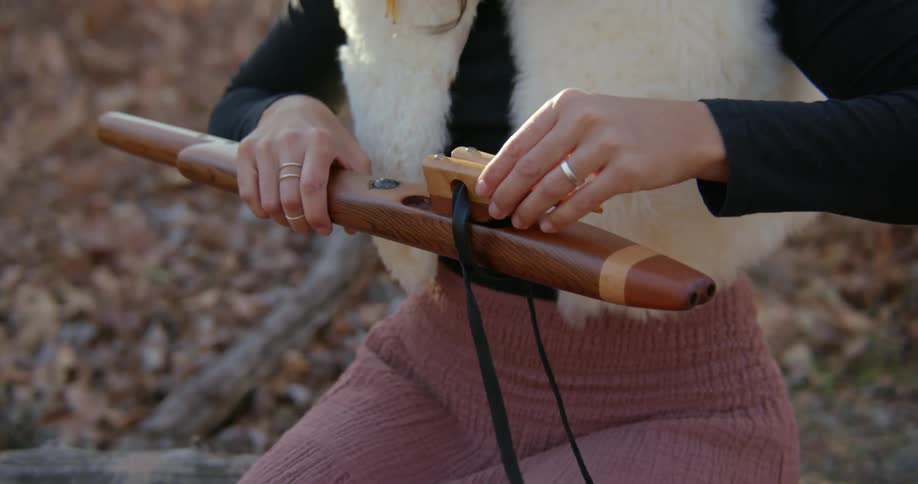 A woman sits on a log while she puts together a device