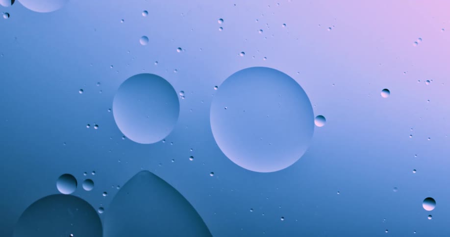 Blobs and bubbles of translucent liquid gently flowing over a blue and magenta background
