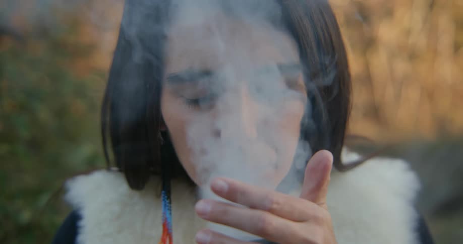 Woman sitting holds a censer burning aromatic incense at evening