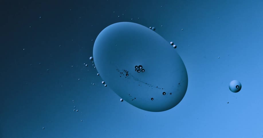 Blobs and bubbles of translucent liquid gently merging over a blue and magenta background