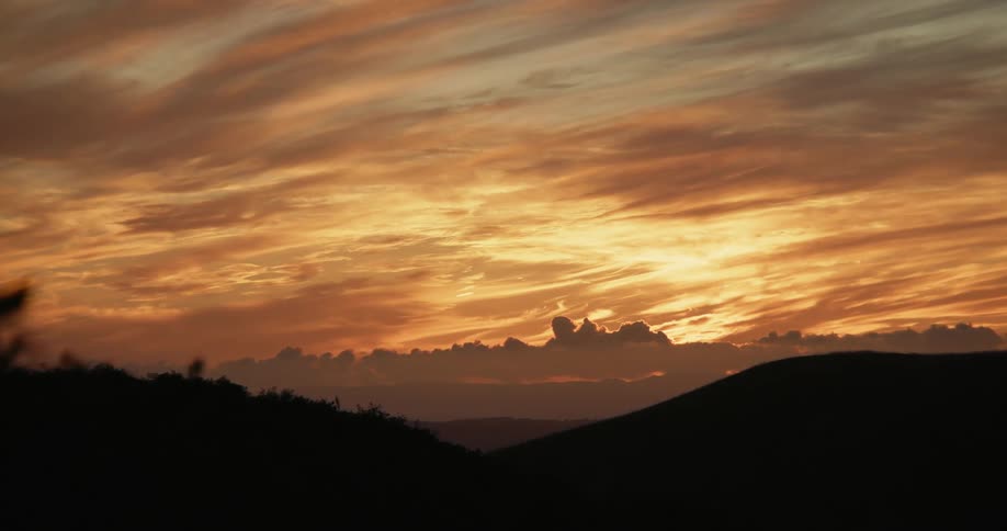 Landscape of hills being silhouetted against the sunset
