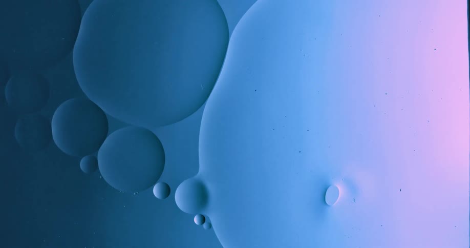 Blobs and bubbles of translucent liquid gently flowing over a blue and magenta background