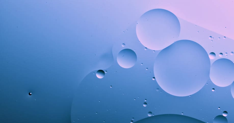 Blobs and bubbles of translucent liquid gently flowing over a blue and magenta background