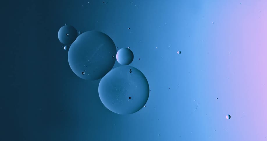 Round bubbles of various sizes floating and growing over a blue and magenta liquid