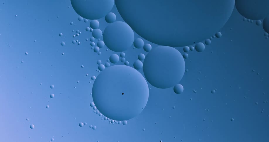 Blobs and bubbles of translucent liquid gently flowing over a blue background