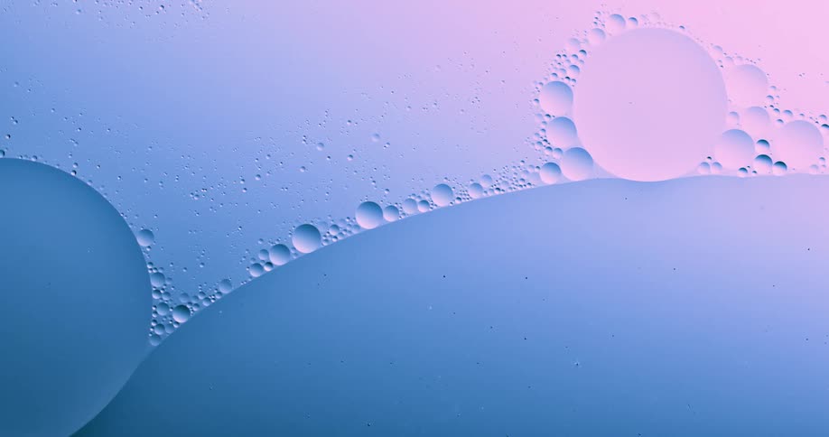 Round bubbles of various sizes floating on a blue and magenta liquid