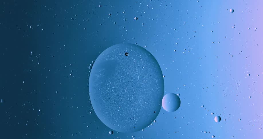 Blobs and bubbles of translucent liquid gently merging over a blue and magenta background