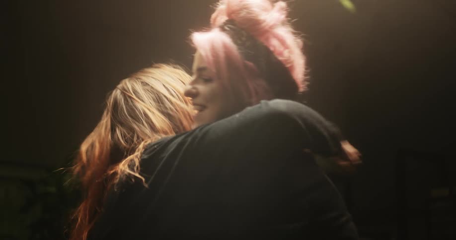 Two women look at a phone and hug