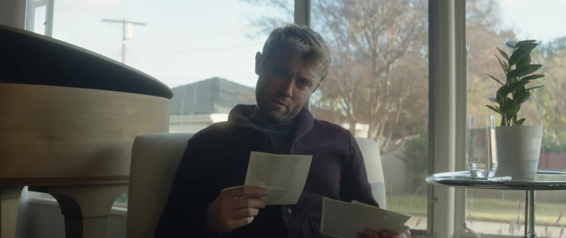 A man looking through a stack of photographs and smiling