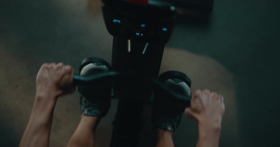 Top down view of a strong muscular man sweating while working out on a rowing machine
