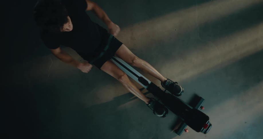 Man wearing black t shirt shorts and sneakers uses pull machine at the gym