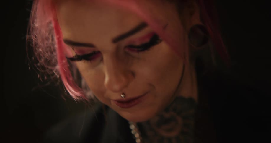 Close up of a tattoo artist with colorful hair working on the skin of a client