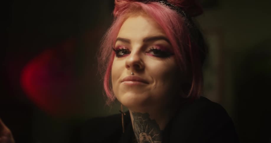 Close up of the face of a tattoo artist with colorful hair drawing on paper