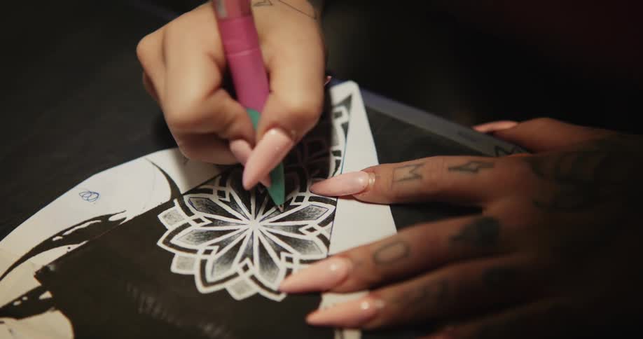 Close up of a tattoo artist sketching on a piece of paper with a pen