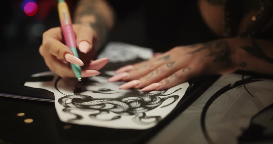 Close up of a tattoo artist sketching on a piece of paper with a pen