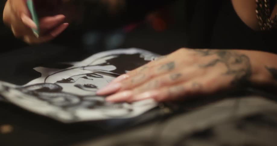 Close up of a tattoo artist sketching on a piece of paper with a pen