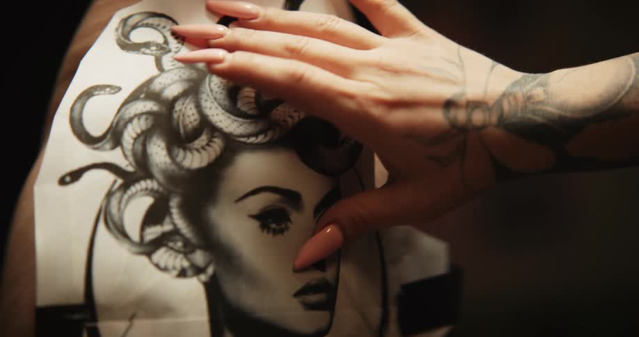 A tattoo artist putting a sketch of a tattoo onto a clients hip and thigh